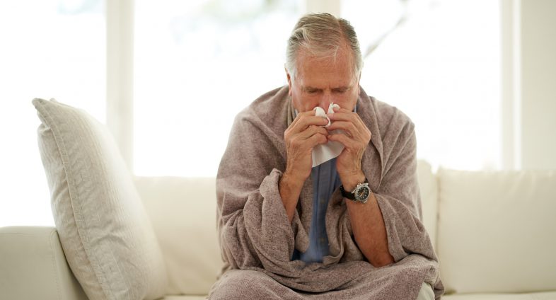 senior man with flu blowing nose