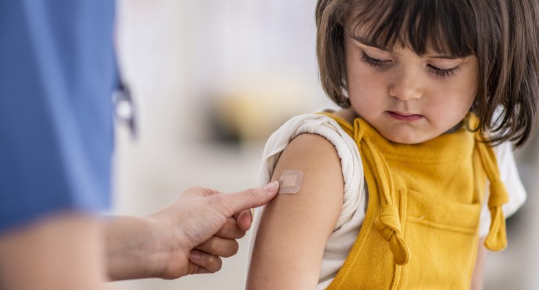 toddler girl looking at bandaid after vaccination