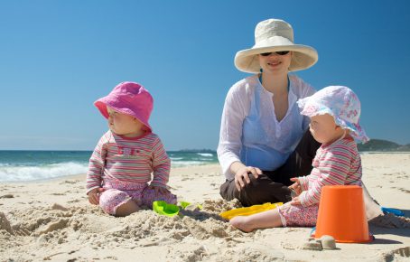 Mom and babies at beach in sun hats